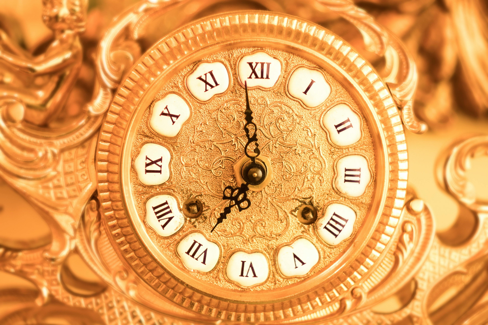 Close-up of a luxurious antique clock with intricate golden detailing and Roman numerals.